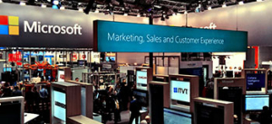 Microsoft-Messestand mit einem groÃŸen Banner mit der Aufschrift â€žMarketing, Vertrieb und Kundenerfahrungâ€œ, umgeben von mehreren AusstellungsstÃ¤nden und Technologieeinrichtungen.