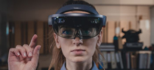 Person, die ein Augmented-Reality-Headset trÃ¤gt und eine Hand hebt, im Hintergrund sind Regale und BÃ¼roausstattung zu sehen.