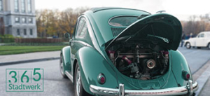 Ein alter grÃ¼ner VW KÃ¤fer steht mit geÃ¶ffneter Heckklappe auf einer StraÃŸe, in der Ecke ist das Logo â€ž365 Stadtwerkâ€œ zu sehen.