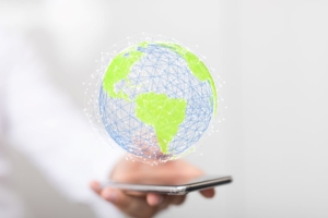 Digitaler Globus mit grÃ¼nen Kontinenten und blauen Netzlinien, der Ã¼ber einem Smartphone schwebt.