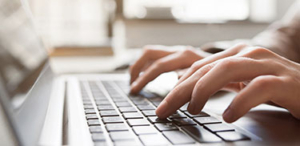 Eine Person, die sich auf das Tippen auf einer Laptoptastatur konzentriert, wobei die HÃ¤nde Ã¼ber den Tasten liegen.