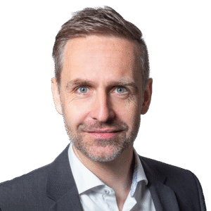 Professionelles Business-PortrÃ¤t, das eine Person in einem formellen Sakko und einem Hemd mit Kragen vor einem neutralen Hintergrund zeigt und UnternehmensfÃ¼hrung, ProfessionalitÃ¤t sowie ein modernes GeschÃ¤ftsumfeld verkÃ¶rpert.