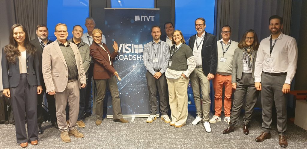 Gruppenfoto der Teilnehmer, die bei einer ITVT-Veranstaltung zusammenstehen und vor einem Hintergrund mit dem ITVT-Logo der VIS Roadshow in einem Konferenzraum posieren.