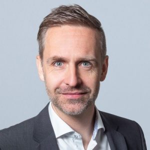 Professionelles Business-PortrÃ¤t, das eine Person in einem formellen Sakko und einem Hemd mit Kragen vor einem neutralen Hintergrund zeigt und UnternehmensfÃ¼hrung, ProfessionalitÃ¤t sowie ein modernes GeschÃ¤ftsumfeld verkÃ¶rpert.